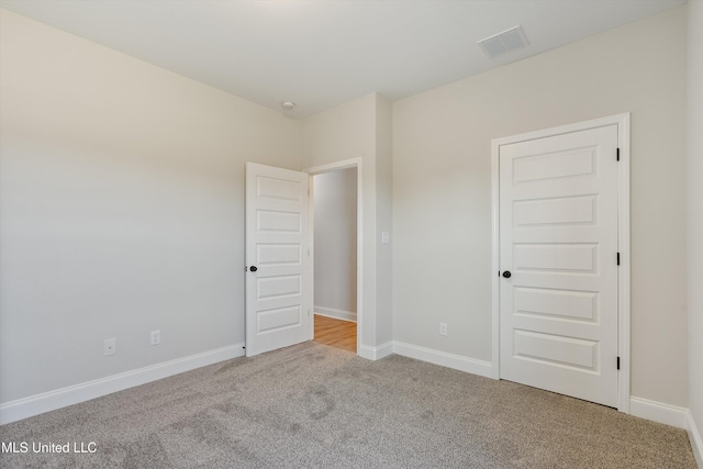 spare room featuring light carpet, baseboards, and visible vents