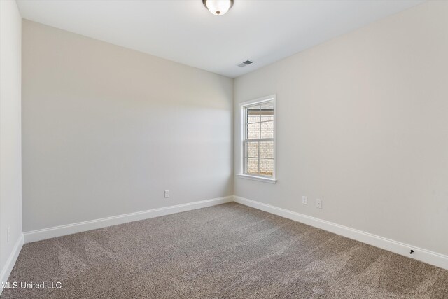 spare room with carpet floors, visible vents, and baseboards