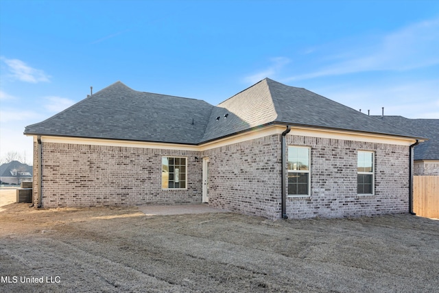 back of house featuring a patio area, roof with shingles, and brick siding