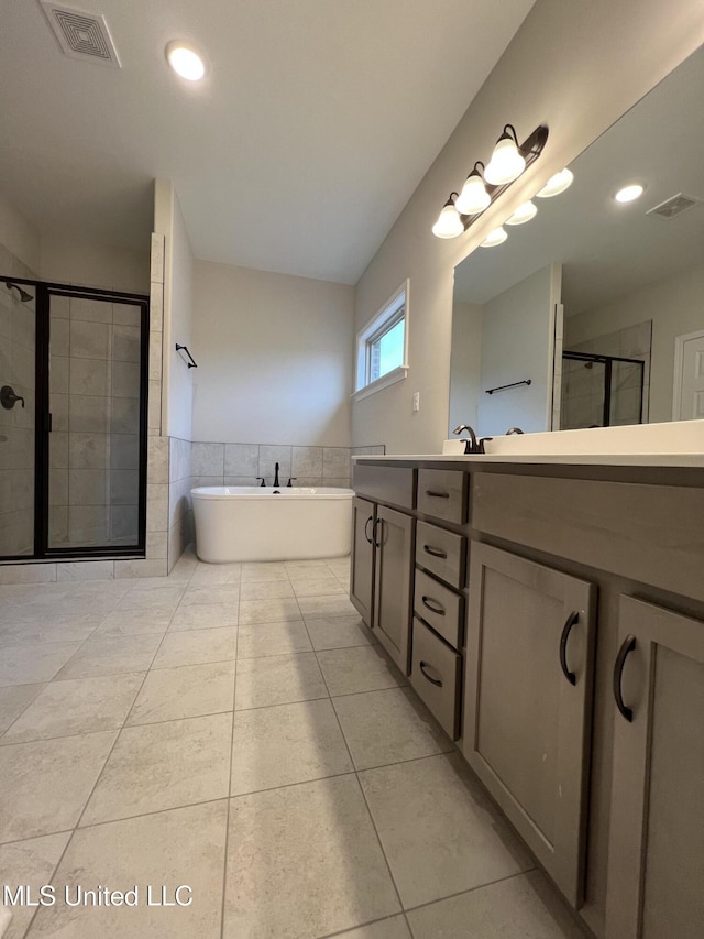 full bath with a freestanding bath, double vanity, tile patterned flooring, and visible vents