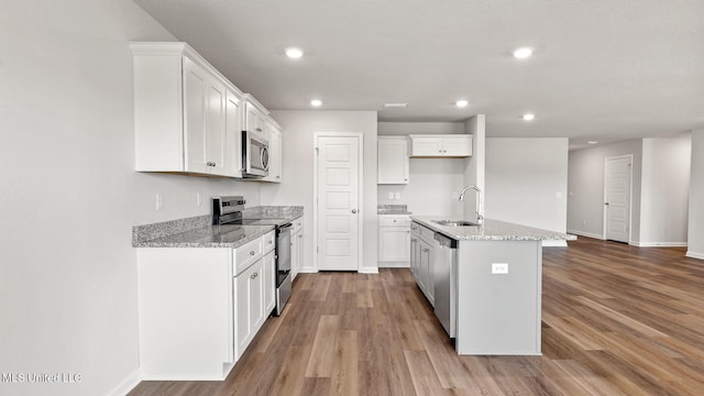 9613 Reserve Blvd, Biloxi, MS 39532 - kitchen featuring appliances with stainless steel finishes, light wood finished floors, recessed lighting, light stone counters, and white cabinetry