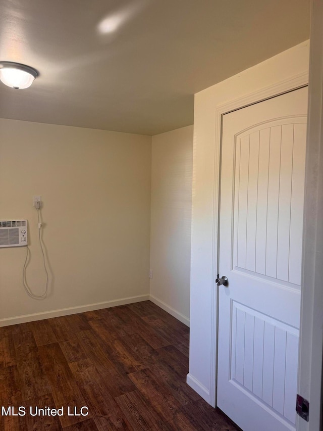 unfurnished room featuring a wall mounted air conditioner and dark wood-type flooring