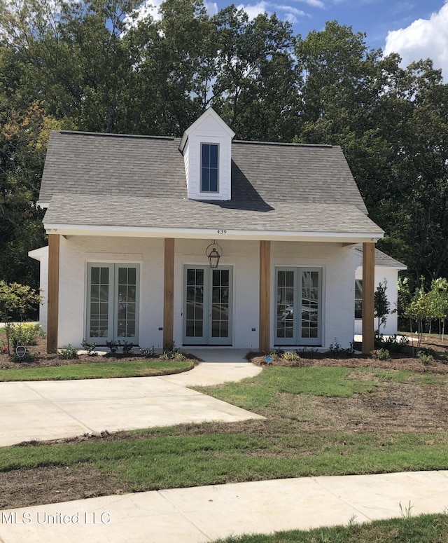 cape cod-style house featuring french doors and a front yard