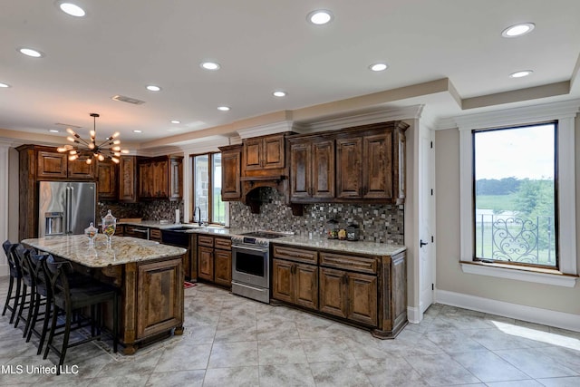 11281 Rd 468, Philadelphia, MS 39350 - kitchen featuring a kitchen bar, hanging light fixtures, light stone counters, stainless steel appliances, and a center island with sink