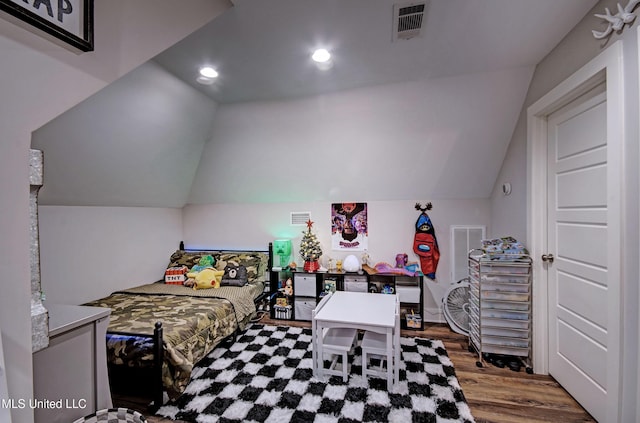 bedroom with visible vents, vaulted ceiling, and wood finished floors