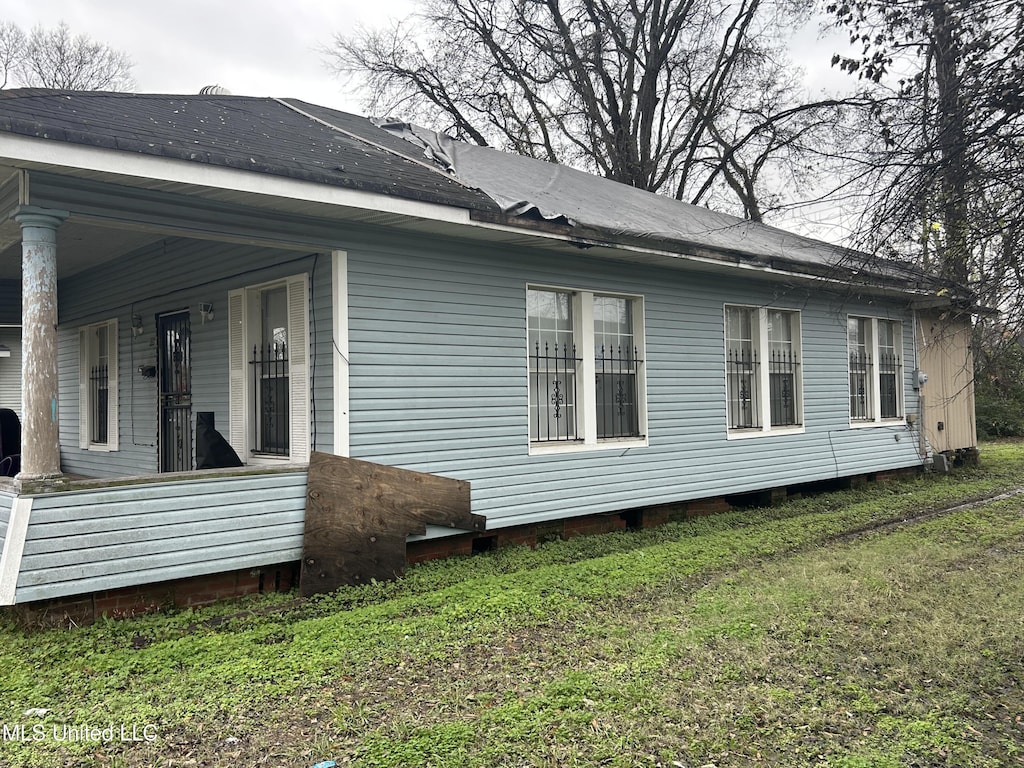 view of side of home with covered porch and a yard