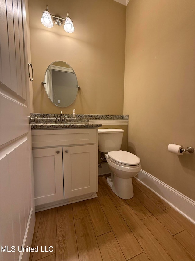 bathroom featuring wood-type flooring, vanity, and toilet