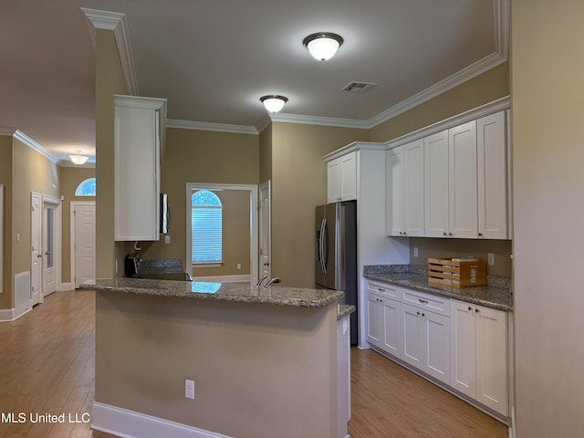 kitchen featuring white cabinets, light wood-type flooring, stainless steel appliances, and light stone countertops