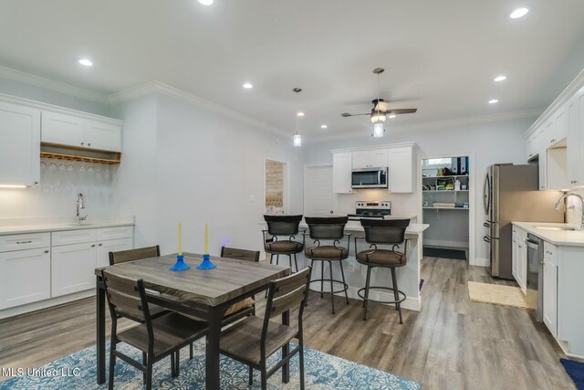 dining space featuring recessed lighting, ornamental molding, a ceiling fan, and wood finished floors