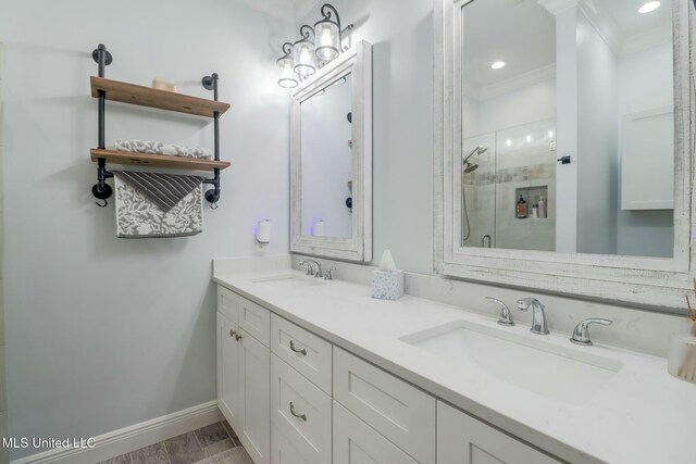 bathroom with crown molding, baseboards, a stall shower, and a sink