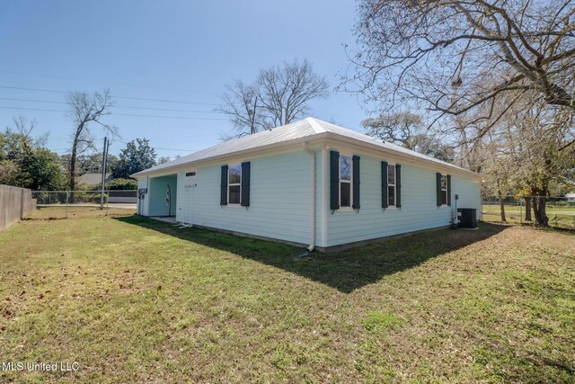 view of property exterior with metal roof, cooling unit, a lawn, and a fenced backyard