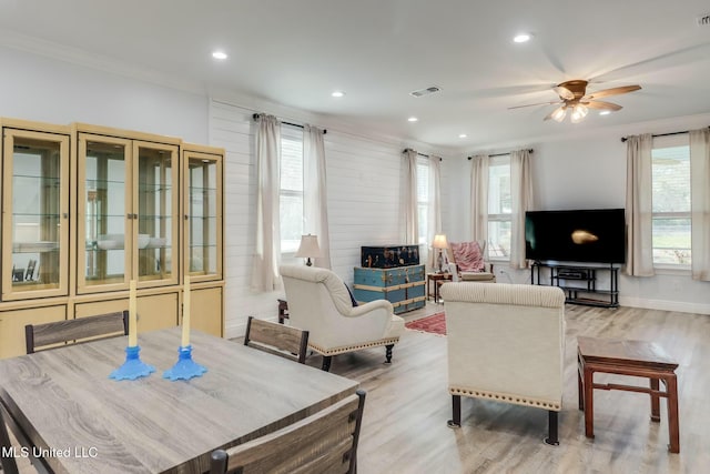 living area featuring a wealth of natural light, visible vents, wood finished floors, and ornamental molding