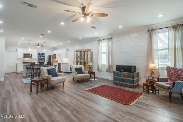 living area with visible vents, wood finished floors, and ceiling fan