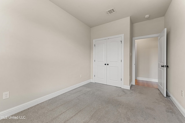 unfurnished bedroom featuring light colored carpet and a closet