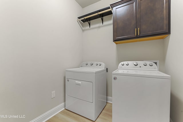 laundry room with washing machine and dryer, cabinets, and light wood-type flooring