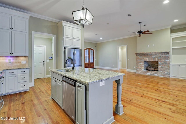 kitchen featuring a kitchen breakfast bar, pendant lighting, a center island with sink, white cabinets, and appliances with stainless steel finishes