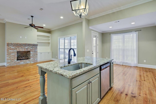 kitchen featuring light stone countertops, stainless steel dishwasher, sink, pendant lighting, and a center island with sink