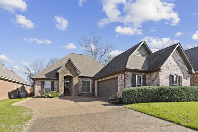 french country style house featuring central AC unit, a front lawn, and a garage