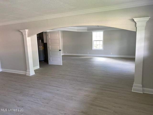 spare room with baseboards, decorative columns, wood finished floors, and electric water heater