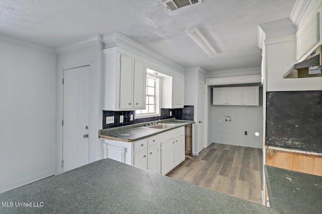 kitchen with dark countertops, wood finished floors, backsplash, a textured ceiling, and white cabinets