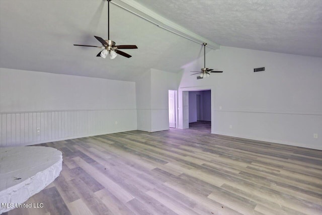 unfurnished room featuring ceiling fan, beam ceiling, wood finished floors, a textured ceiling, and high vaulted ceiling