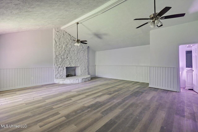 unfurnished living room featuring a ceiling fan, wood finished floors, a fireplace, and a textured ceiling