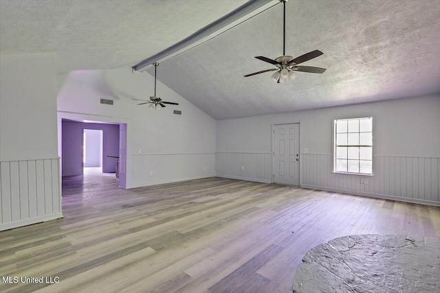 unfurnished living room featuring a ceiling fan, wood finished floors, a textured ceiling, and wainscoting