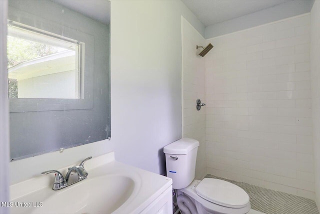 full bath featuring toilet, tiled shower, and vanity