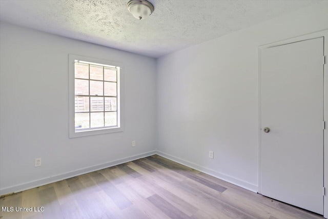 empty room featuring wood finished floors, a textured ceiling, and baseboards