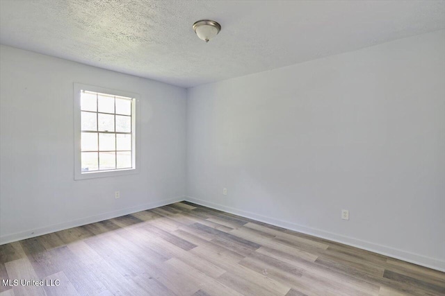 empty room featuring wood finished floors, baseboards, and a textured ceiling