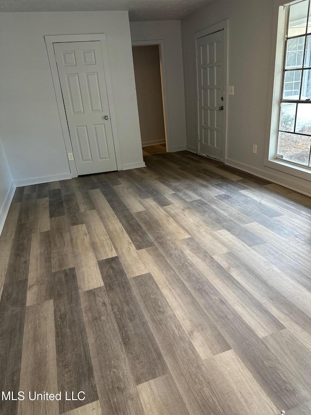 spare room featuring dark wood-style flooring and baseboards