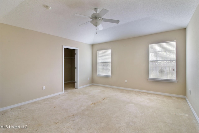 unfurnished bedroom with baseboards, carpet, a spacious closet, a textured ceiling, and a closet