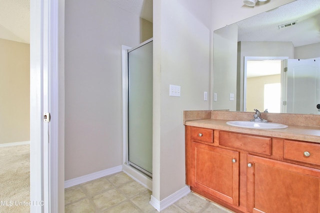 bathroom featuring a shower stall, visible vents, baseboards, and vanity