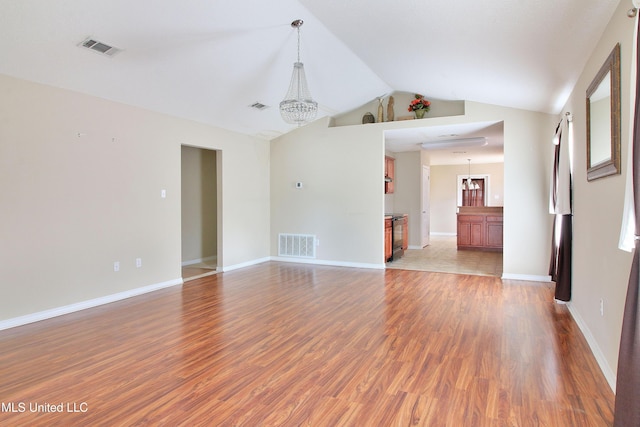 unfurnished room with lofted ceiling, visible vents, and wood finished floors