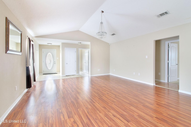 unfurnished living room featuring lofted ceiling, light wood finished floors, a chandelier, and visible vents