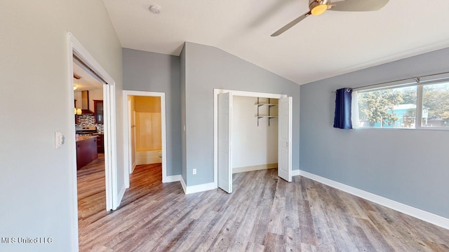 unfurnished bedroom featuring ceiling fan, light hardwood / wood-style floors, vaulted ceiling, and a closet