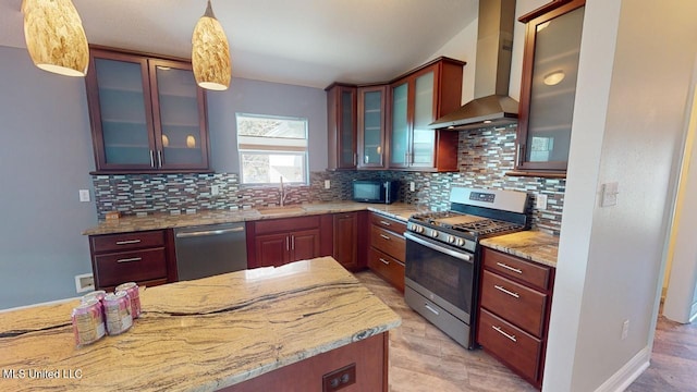 kitchen featuring sink, decorative light fixtures, appliances with stainless steel finishes, light stone countertops, and wall chimney range hood