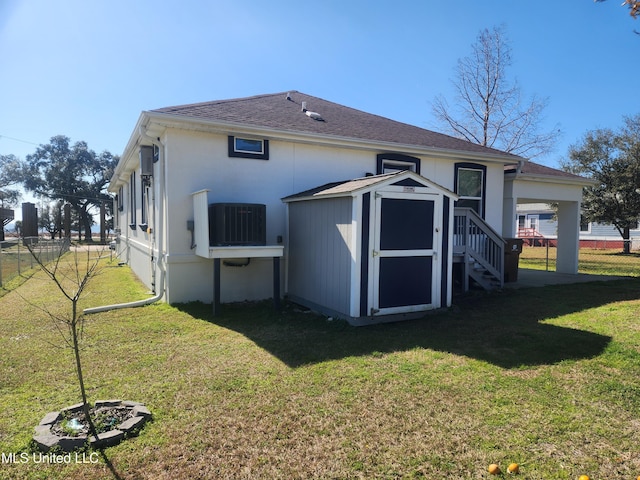 rear view of property featuring a yard, cooling unit, and a storage shed