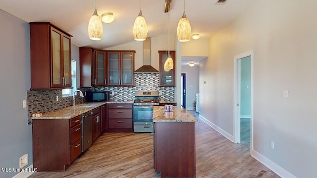 kitchen with pendant lighting, stainless steel appliances, a kitchen island, decorative backsplash, and wall chimney exhaust hood