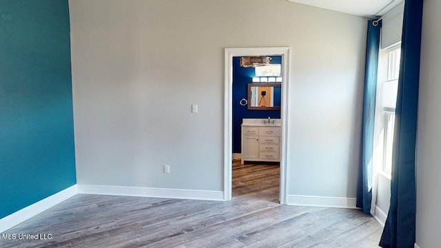 unfurnished room with vaulted ceiling, sink, light wood-type flooring, and a wealth of natural light