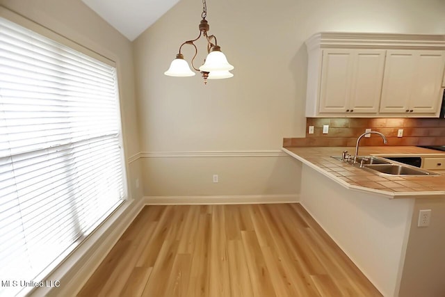 503 W Abbey Pl, Brandon, MS 39047 - kitchen with light wood-style flooring, tile countertops, decorative backsplash, pendant lighting, and a chandelier