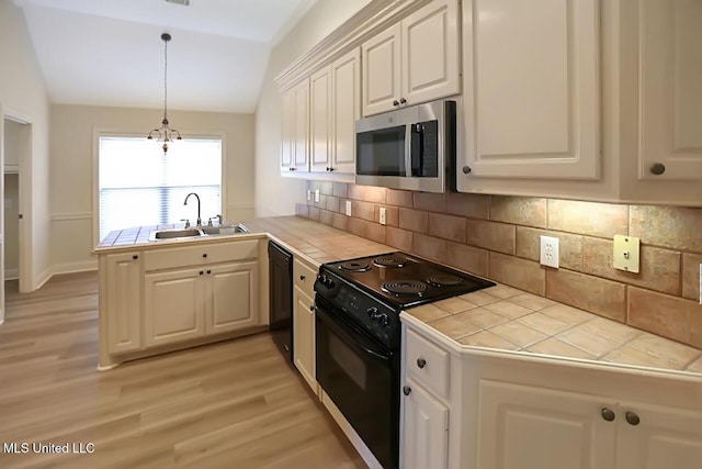 503 W Abbey Pl, Brandon, MS 39047 - kitchen featuring black appliances, tile counters, lofted ceiling, light wood-type flooring, and a peninsula