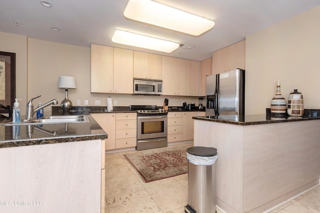 kitchen with dark stone countertops, sink, light brown cabinetry, and appliances with stainless steel finishes