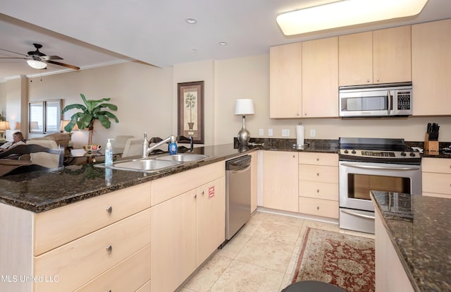 kitchen featuring ceiling fan, sink, stainless steel appliances, kitchen peninsula, and dark stone countertops