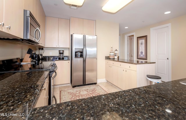 kitchen featuring kitchen peninsula, stainless steel appliances, and dark stone counters