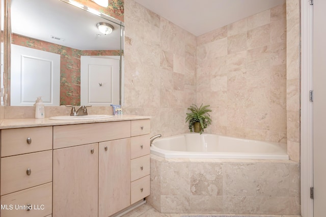 bathroom featuring vanity and tiled tub