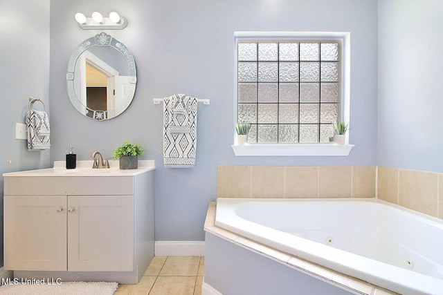 bathroom with tile patterned flooring, vanity, a tub with jets, and baseboards