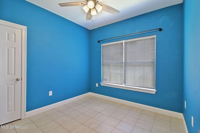 spare room with light tile patterned floors, baseboards, a wealth of natural light, and ceiling fan