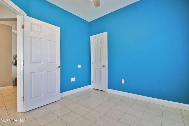 unfurnished bedroom with light tile patterned floors, a ceiling fan, and baseboards