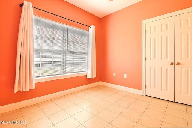 spare room with baseboards and light tile patterned flooring